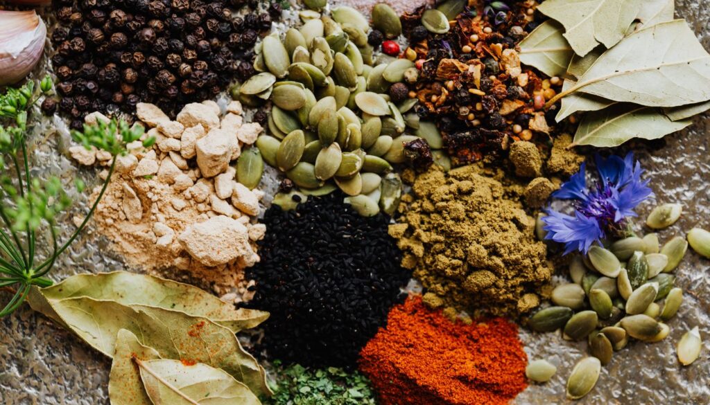 An overhead spread of contrasting dried herbs and spices, echoing how vata, pitta and kapha each carry a different set of qualities