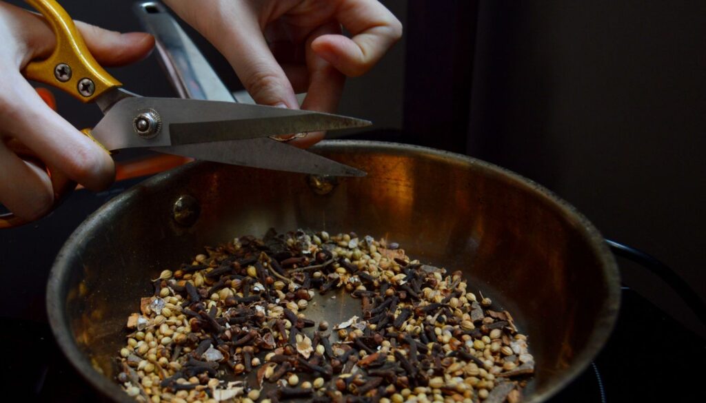 Whole spices toasting in a copper pan, the tempering step that wakes up the aroma of cumin before it goes into a dish